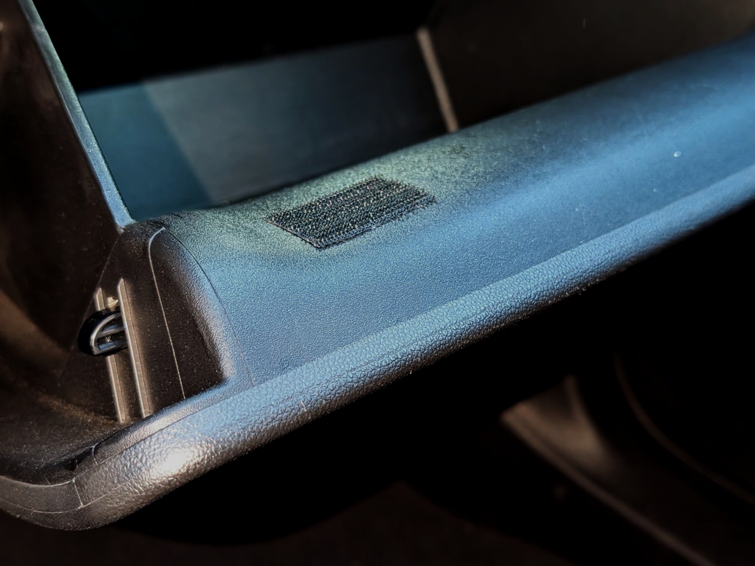 Hook and loop fastener properly attached to glovebox surface showing correct placement and positioning